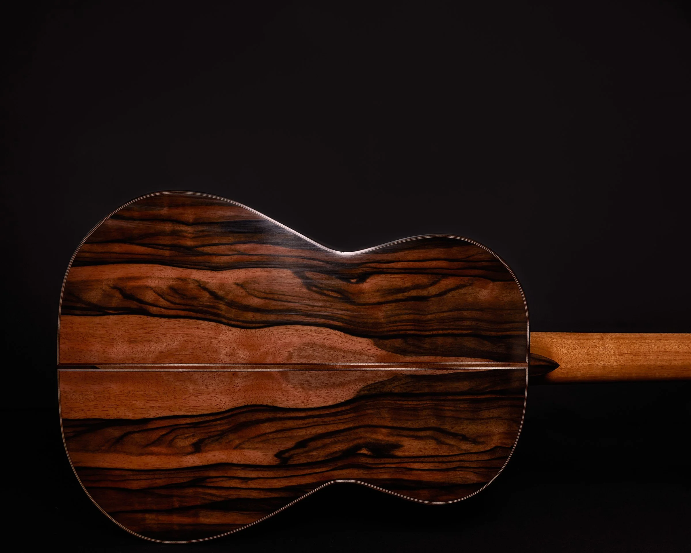 Bookmatched back of a handmade DeMers classical guitar photographed against a black studio background.