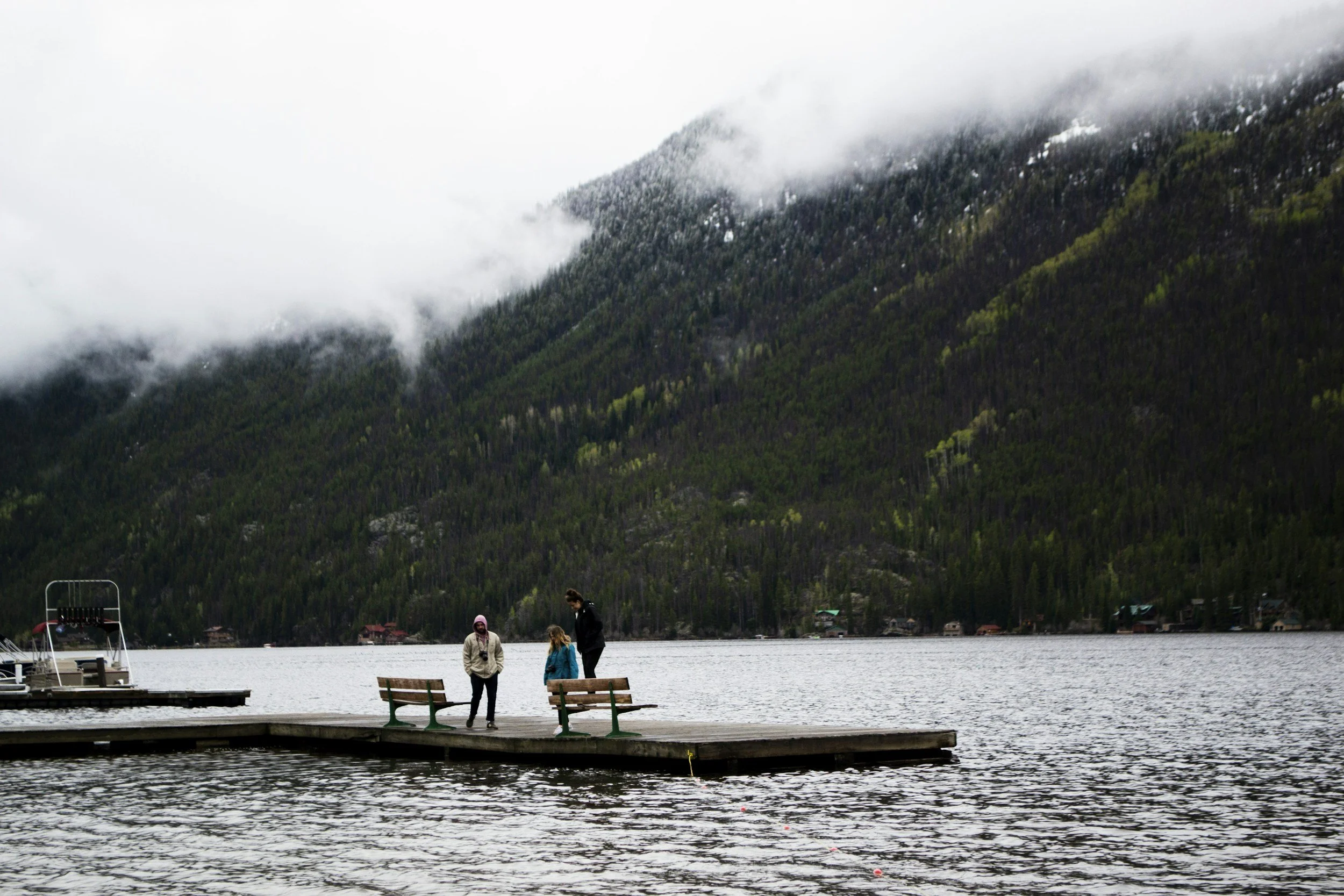 Couple holding hands beside a still mountain lake