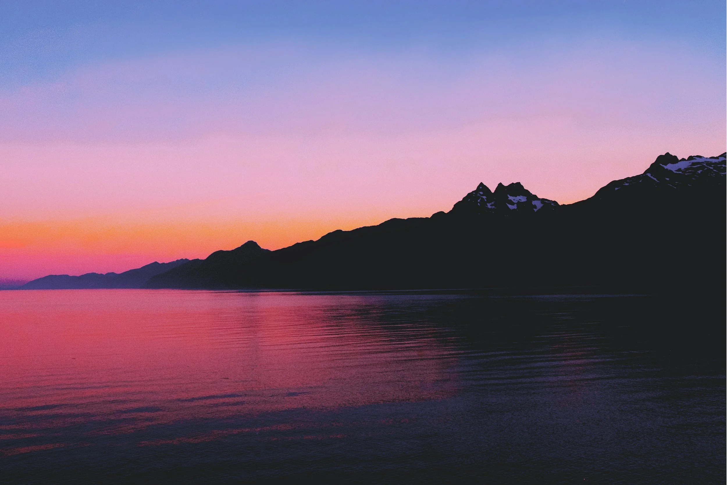 Mountain lake reflecting a pink and orange sunset sky