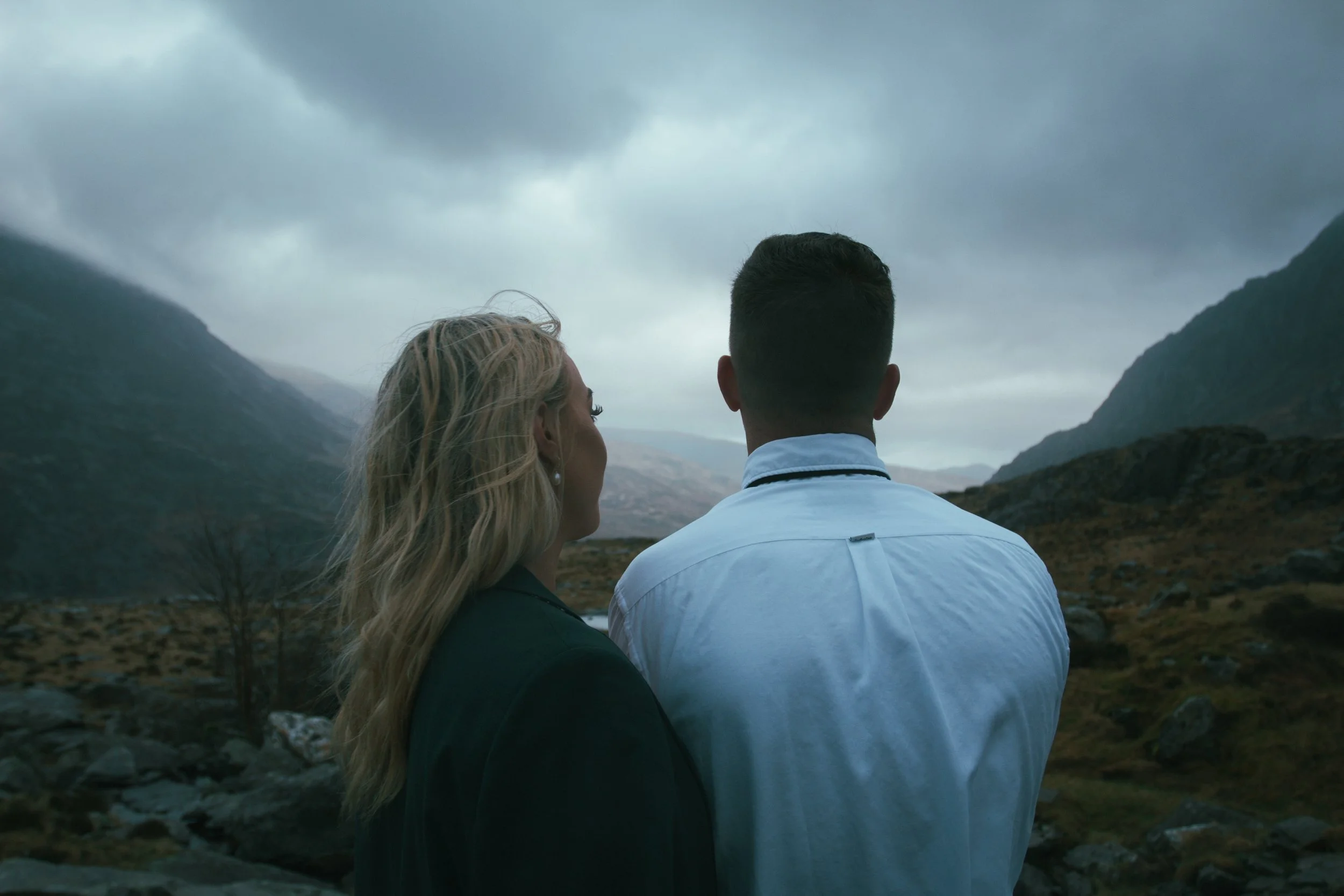 A couple seen from behind, gazing across a mountain valley