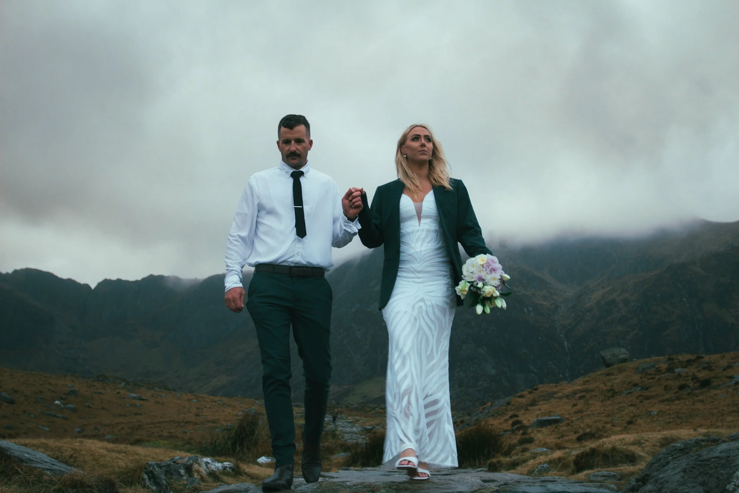 A couple walking hand in hand along a misty mountain path
