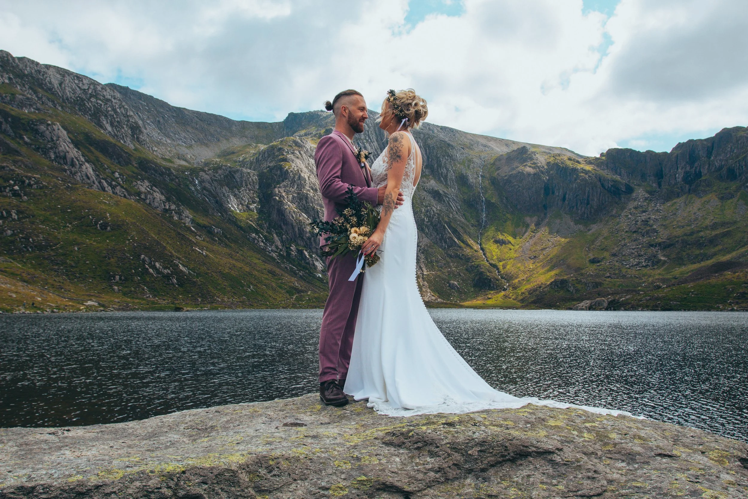 Couple kissing on a rock beside a mountain lake after their elopement