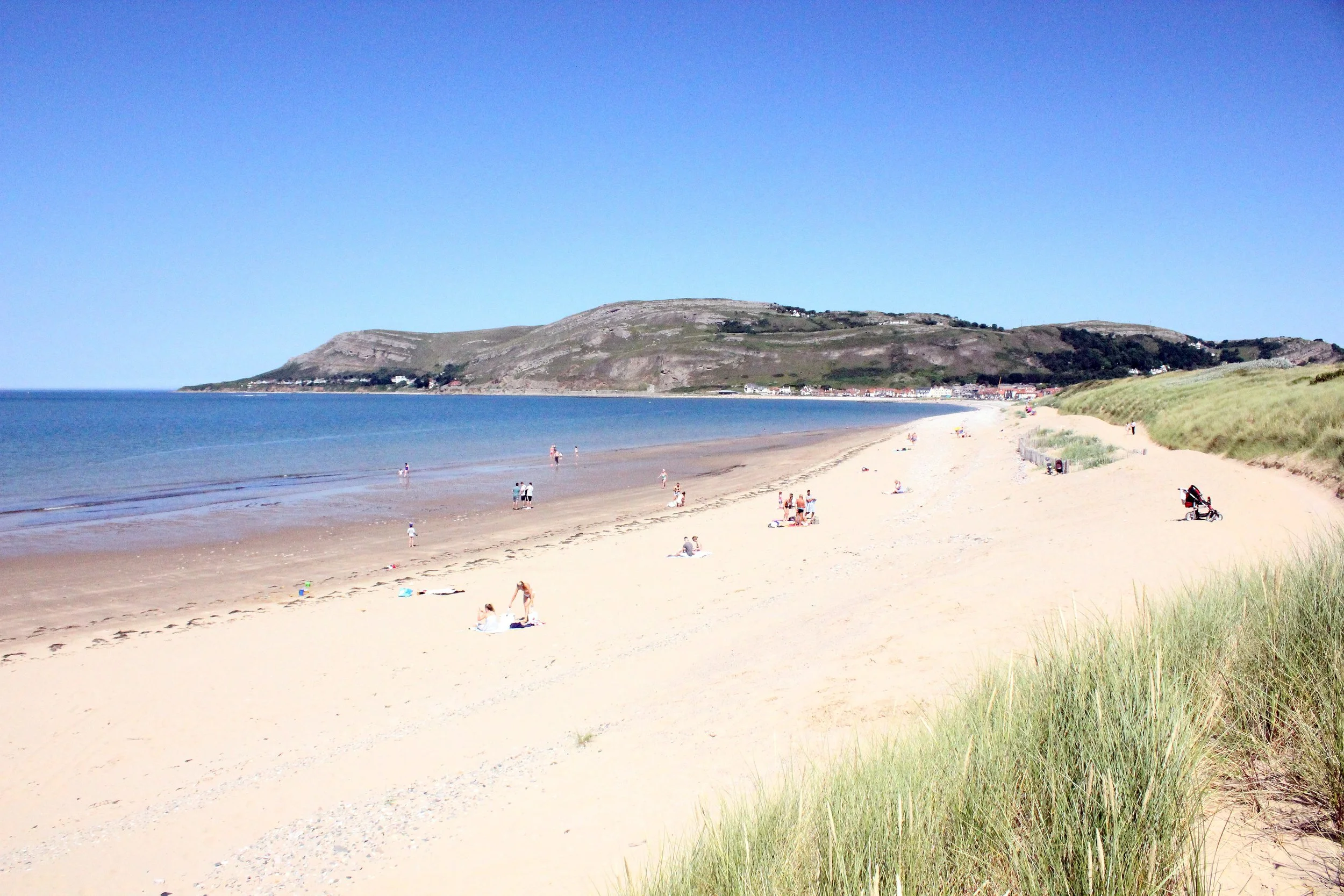 The sandy beach and dunes at West Shore, Llandudno, with the Great Orme in the distance on a sunny day