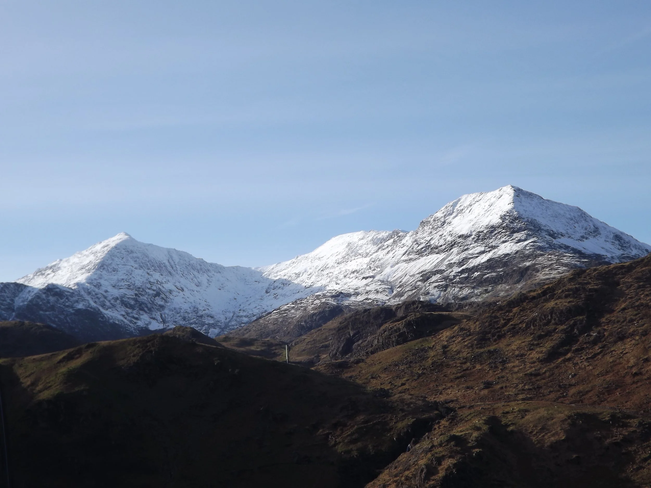 Snow-covered peaks of the Snowdon massif under a clear blue winter sky