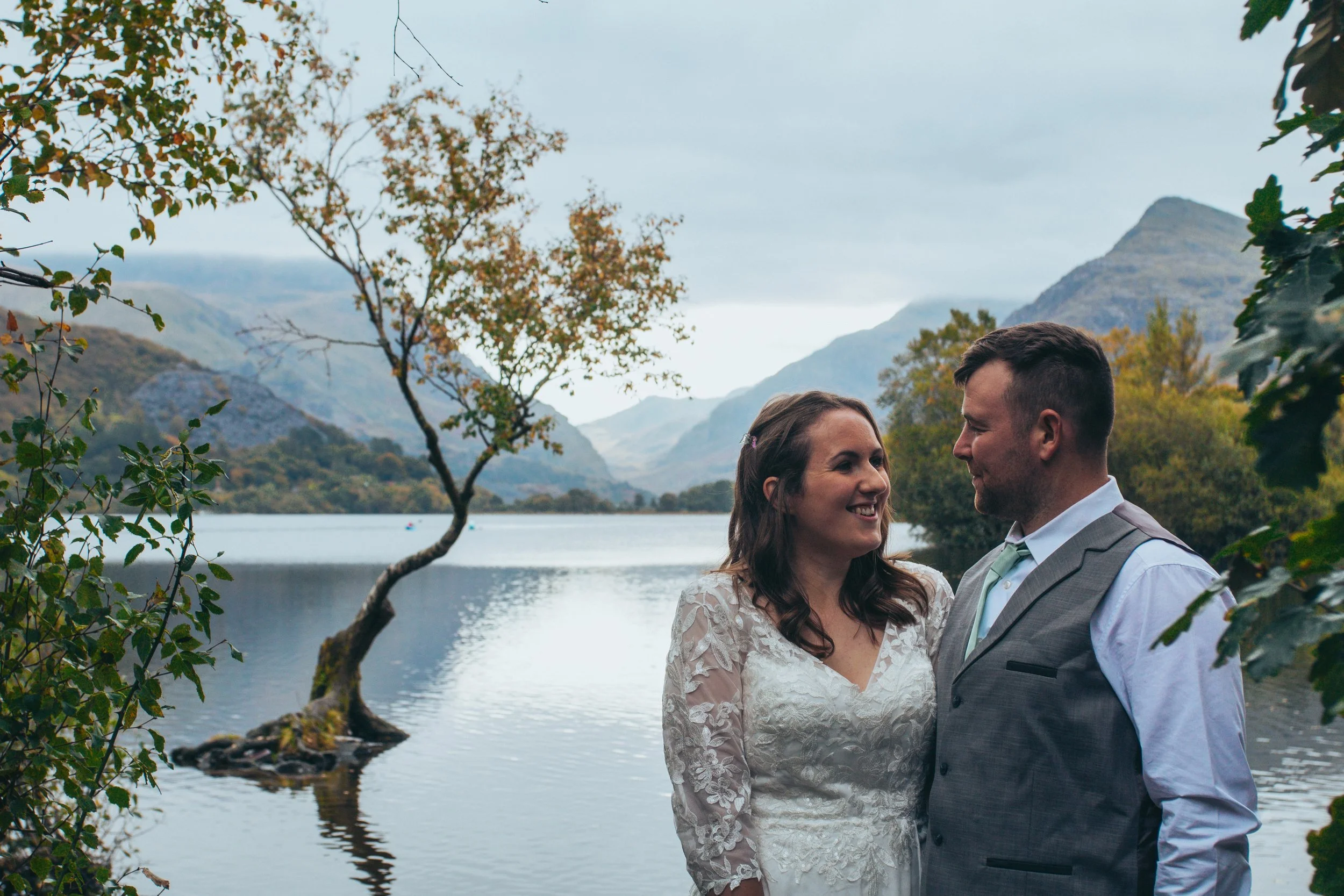 Couple smiling at each other beside a lone tree in a lake