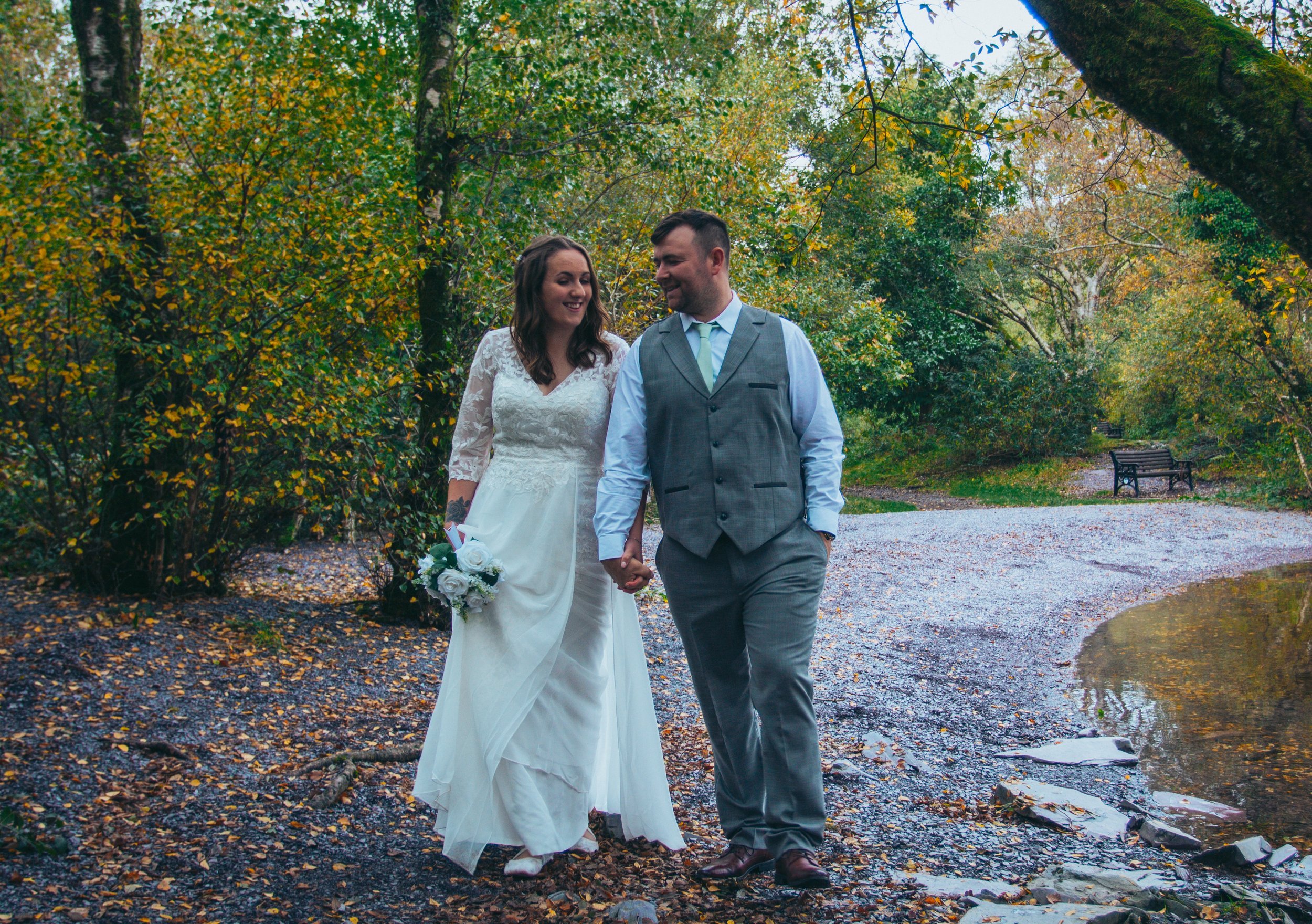 A couple walking hand in hand on a woodland path in autumn