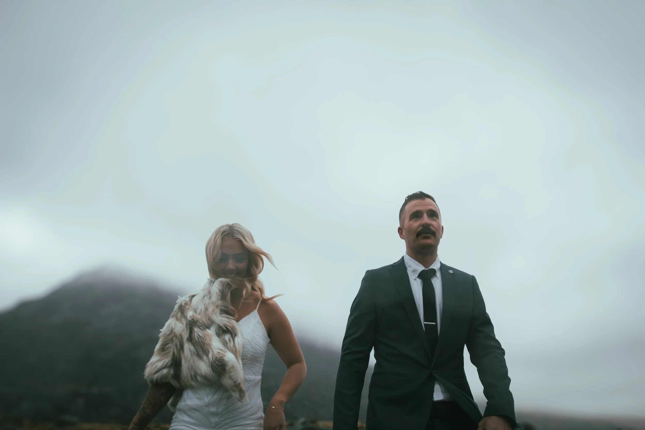 Couple walking together on a misty, windswept hillside