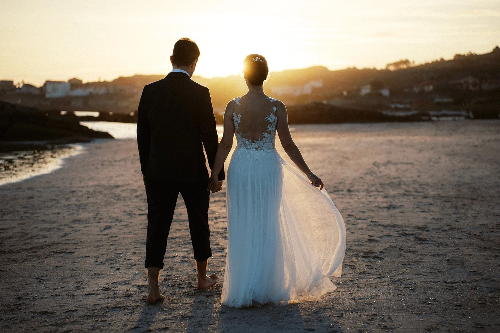 Bride and groom walking barefoot along a Costa del Sol beach at sunset, captured during a romantic destination wedding in Spain.