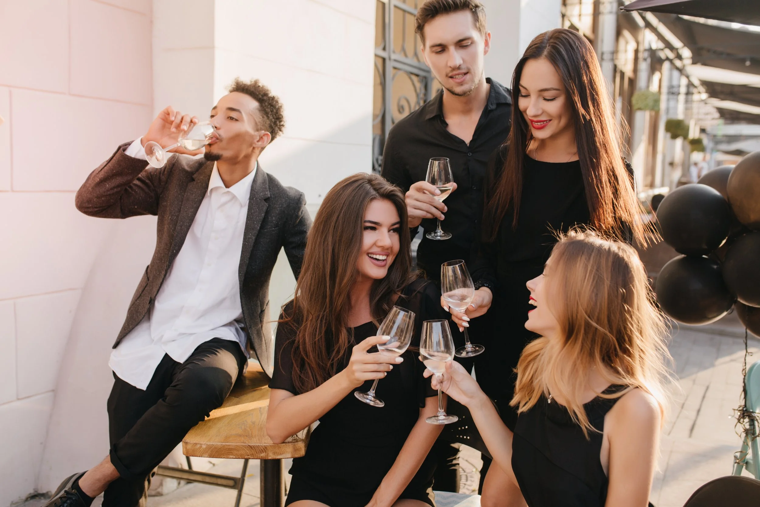 Group of friends enjoying a stylish cocktail event in Marbella, with wine, laughter, and outdoor evening ambience on the Costa del Sol.