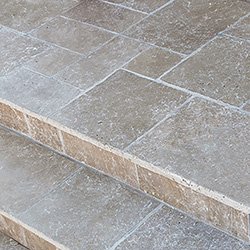 Close-up of stone or concrete stairs with textured surface and straight edges.