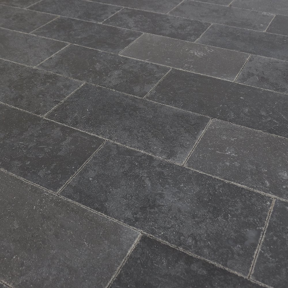 Close-up of a dark gray stone tile floor with rectangular tiles arranged in a pattern.