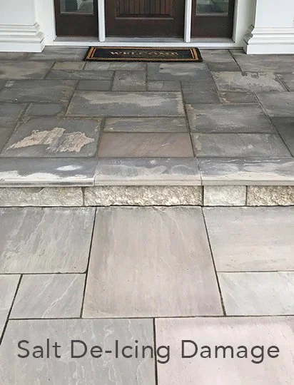 Front porch with damaged salt de-icing residue on gray stone tiles, showing salt corrosion damage.