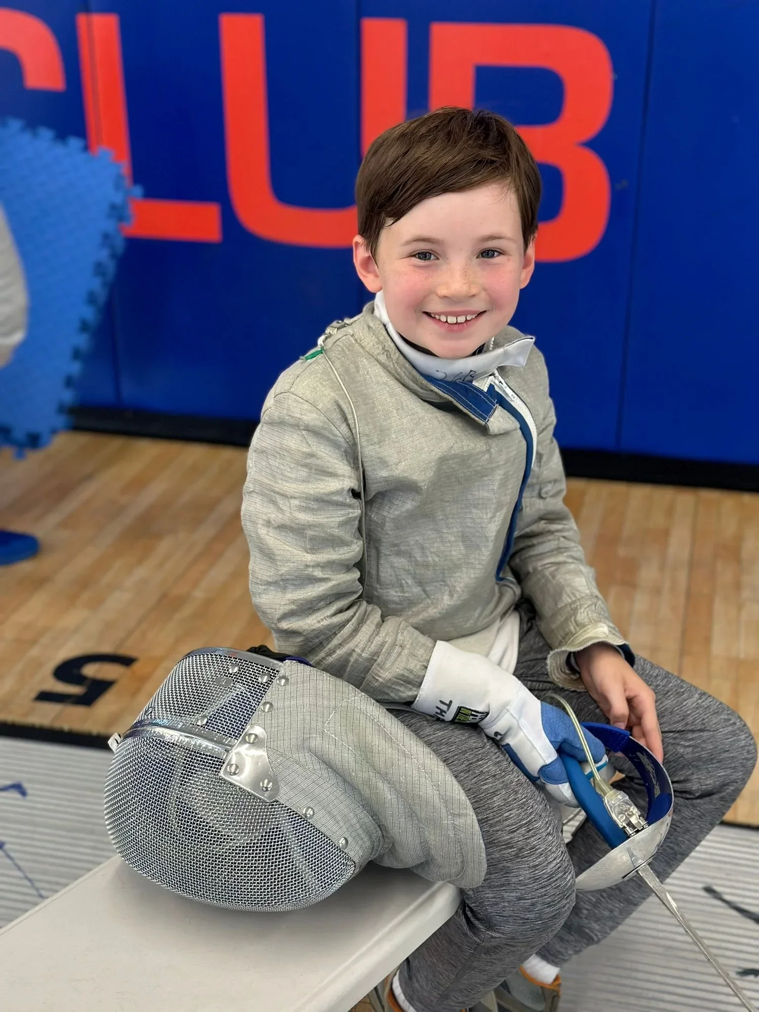 Young TMFC fencer smiling in fencing gear