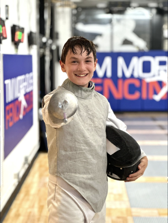 Smiling youth fencer in full kit