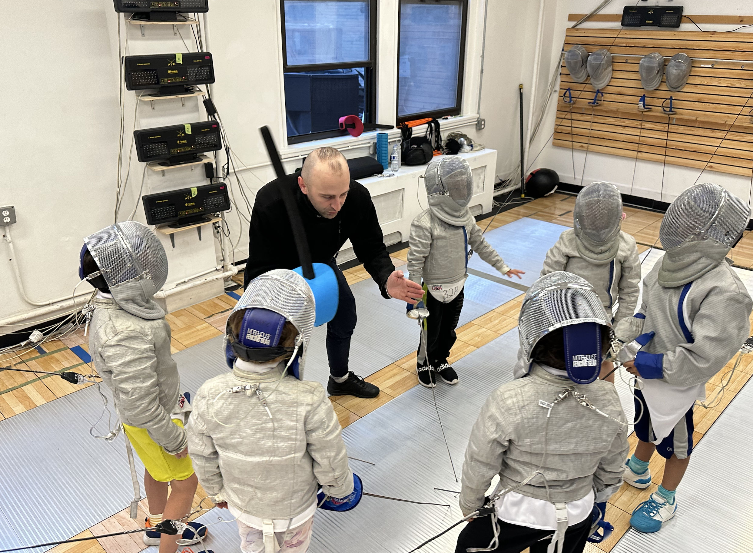 TMFC Upper West Side fencing club — coach instructing young fencers in saber at 91st & Broadway