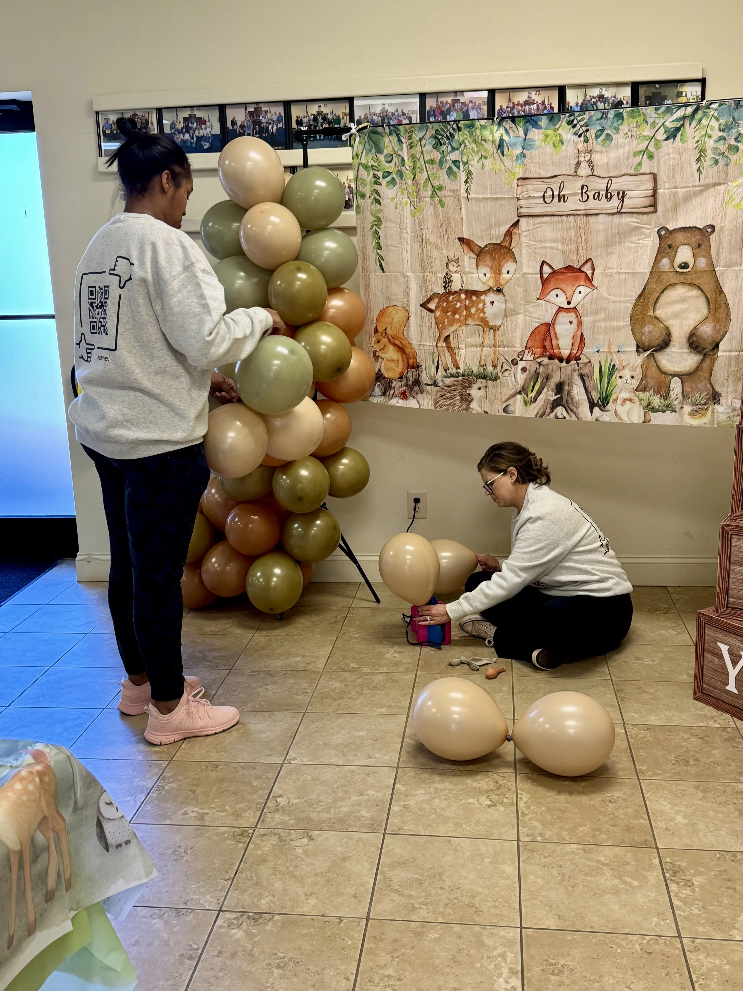 woodland themed balloon arch with animal balloons, oh baby banner, two event workers
