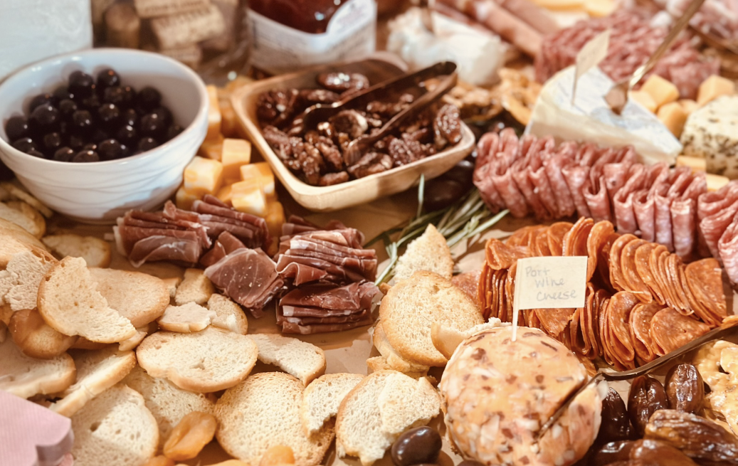 Photo of a charcuterie board with cheese, crackers, cured meats, grapes, and jams.