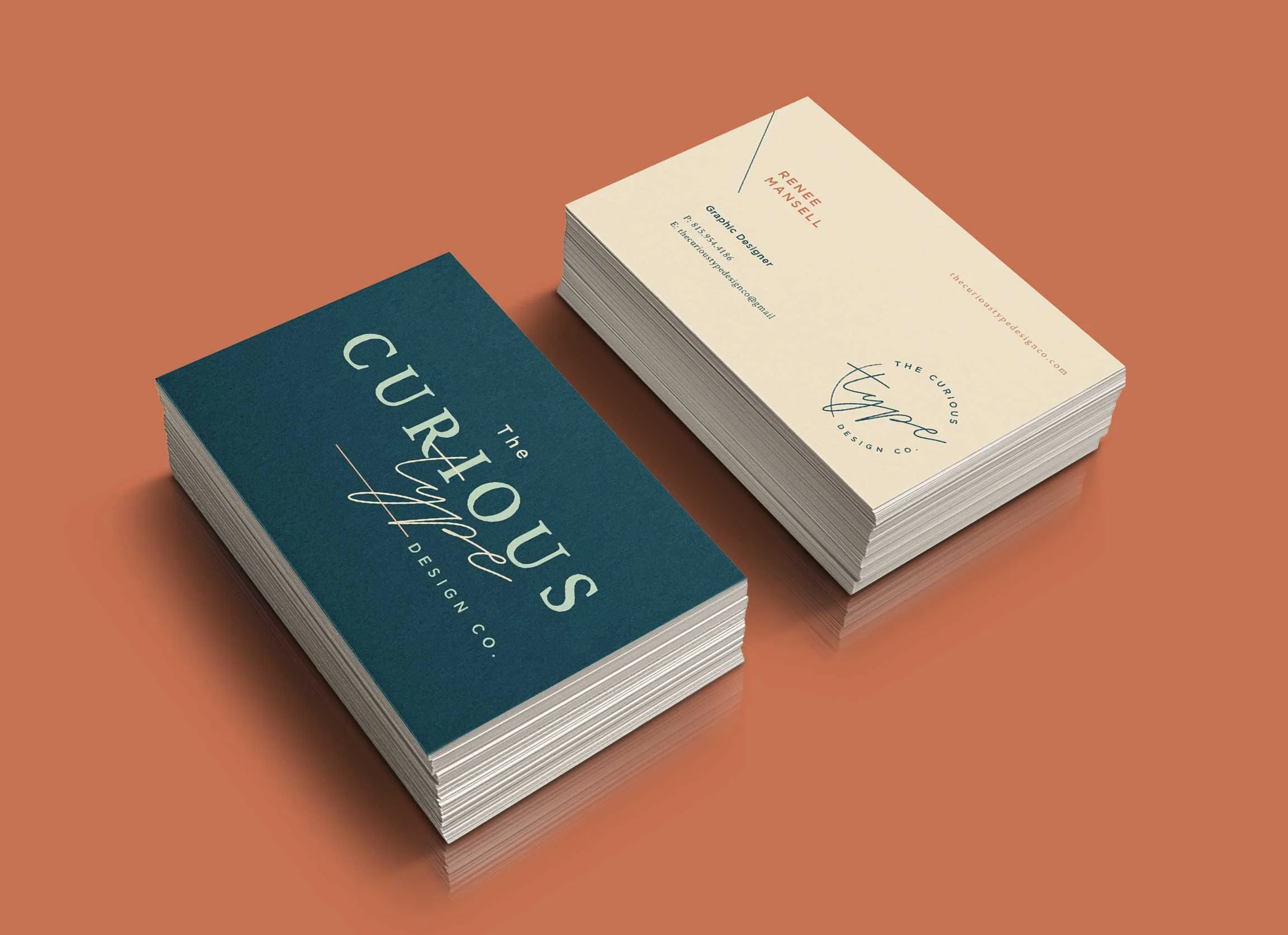 Two stacks of business cards on a peach-colored surface, one with a navy blue background and the other with a beige background, both for 'The Curious Curve Design Co.' with contact details and branding.