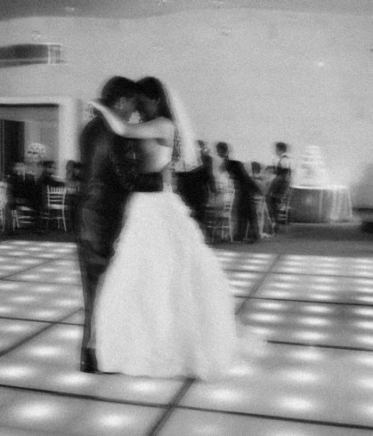 A couple dancing closely on a dance floor at a wedding or event.