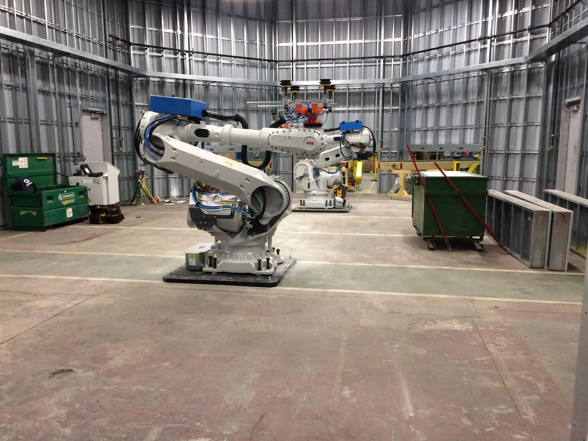 Industrial robotic arm inside a metal-walled manufacturing facility.