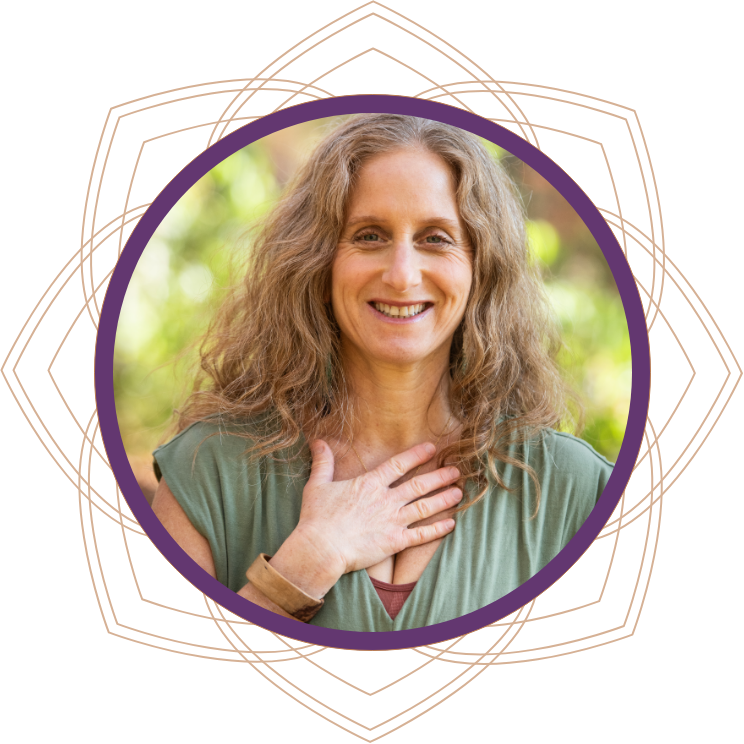 A woman with curly blonde hair smiling outdoors, with her hand on her chest, wearing a green top.