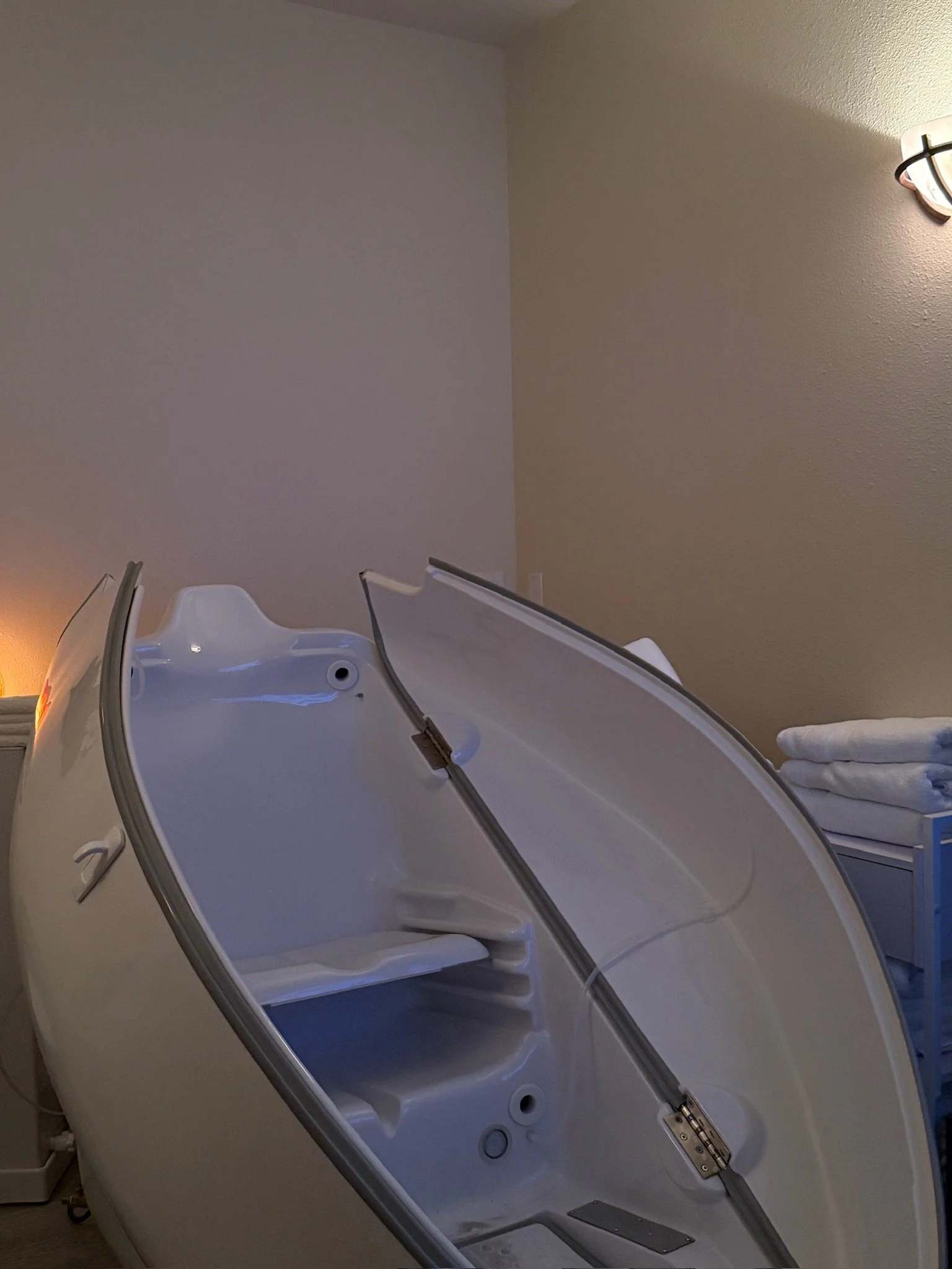 Hocatt therapy pod at a Day Spa Surprise AZ, Med Spa Surprise AZ, with an open lid and folded towels on a side table.