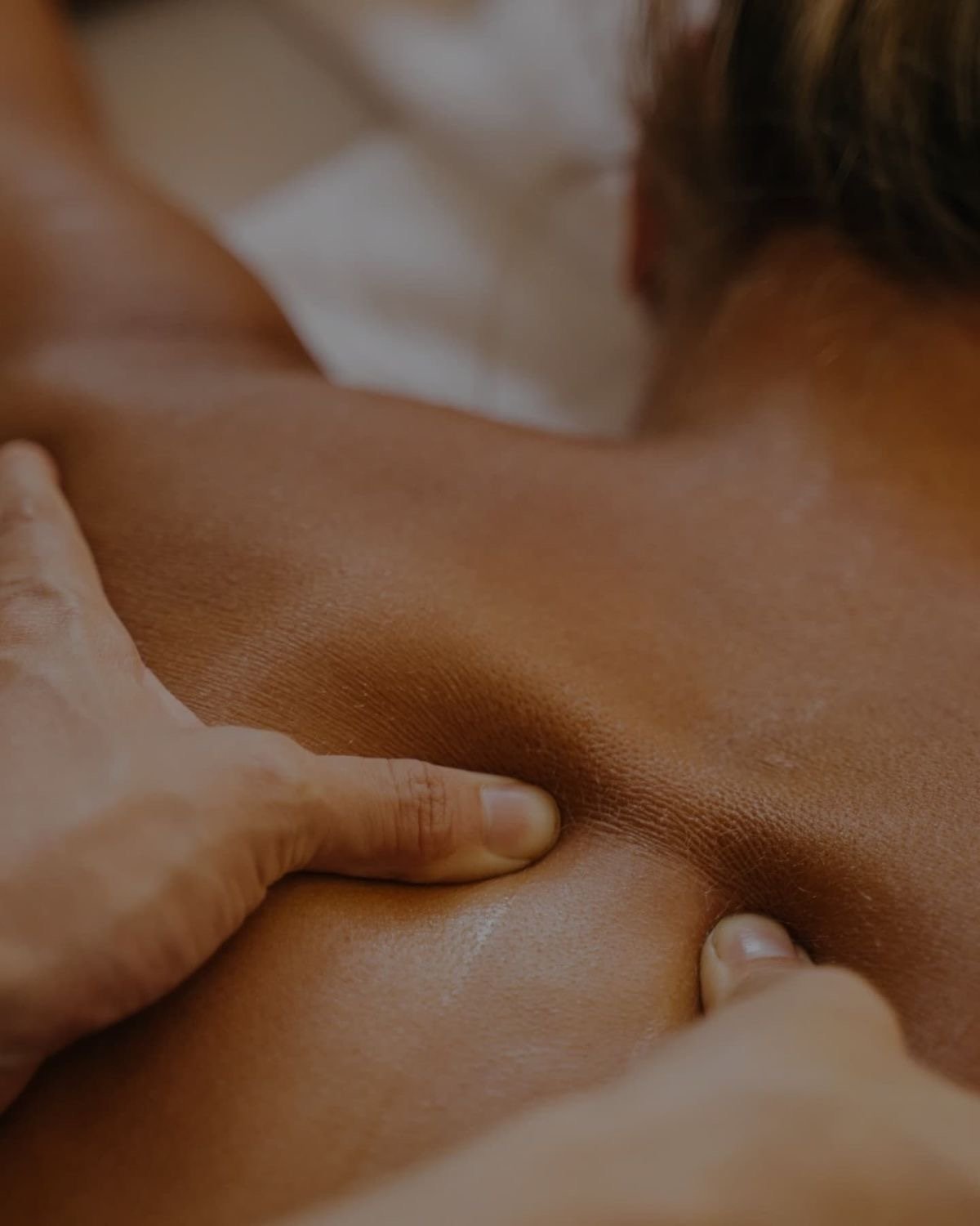 Close-up of a person's back being massaged or touched by hands.