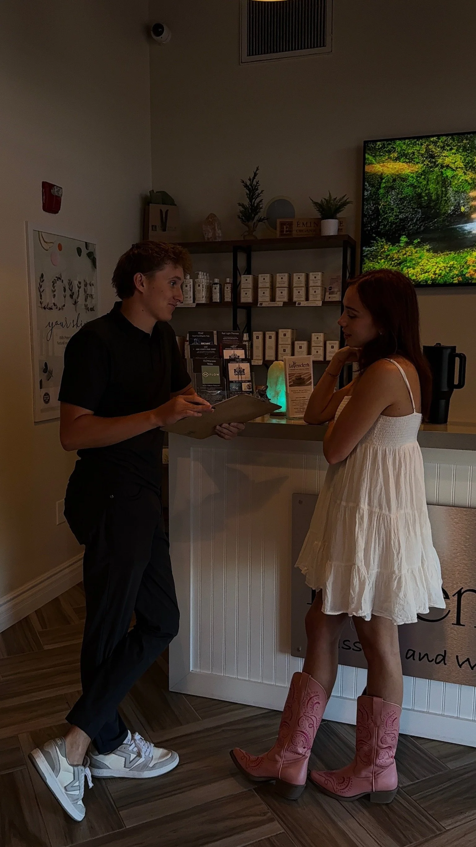 A man and a woman in a Day Spa Surprise AZ, Med Spa Surprise AZ, discussing services, with the woman wearing pink cowboy boots."