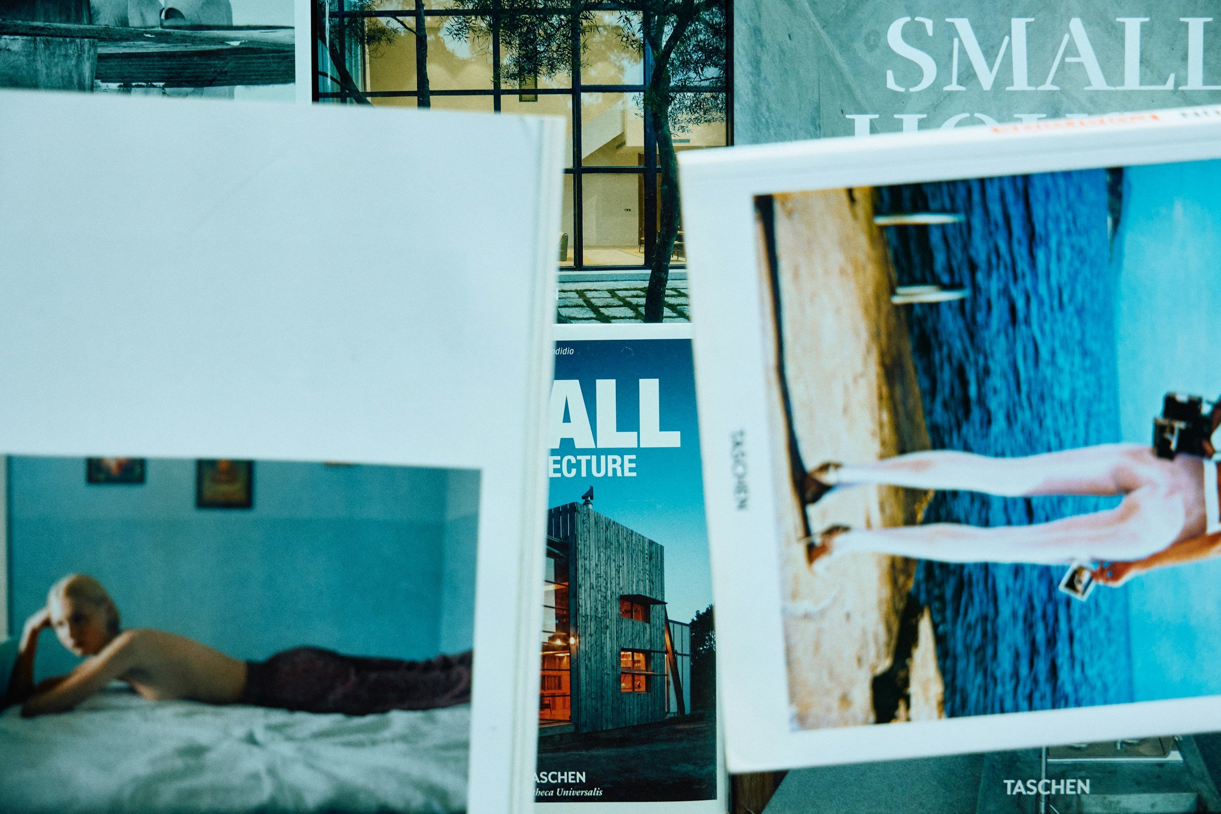 Stack of photography and art books featuring portrait, architectural, and lifestyle imagery displayed on a neutral surface.