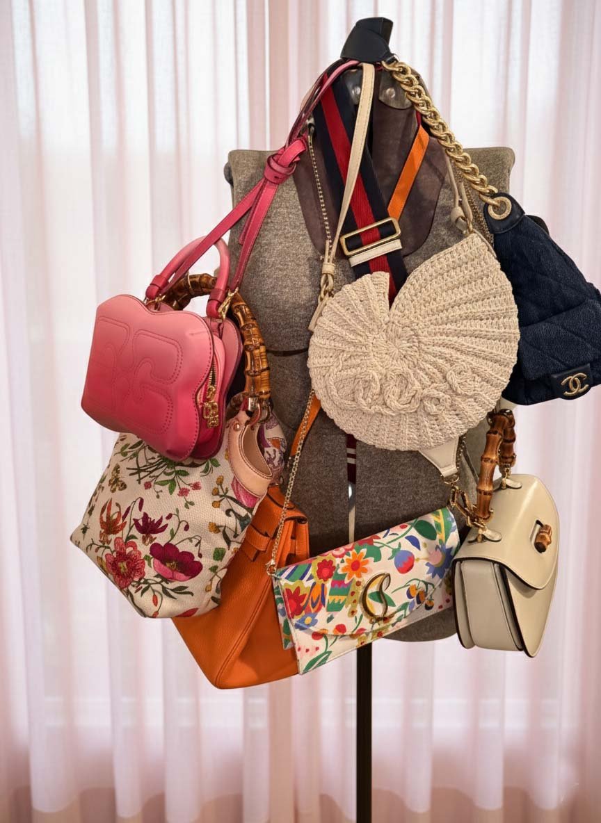 Display of multiple handbags hanging on a mannequin with a fabric torso, set against a light-colored curtain background.