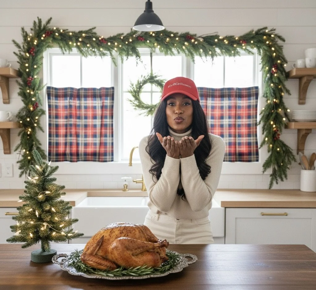 A woman wearing a red cap and beige turtleneck blowing a kiss in a holiday kitchen decorated with Christmas greenery and lights, with a whole roasted turkey on the table and a small lit Christmas tree.