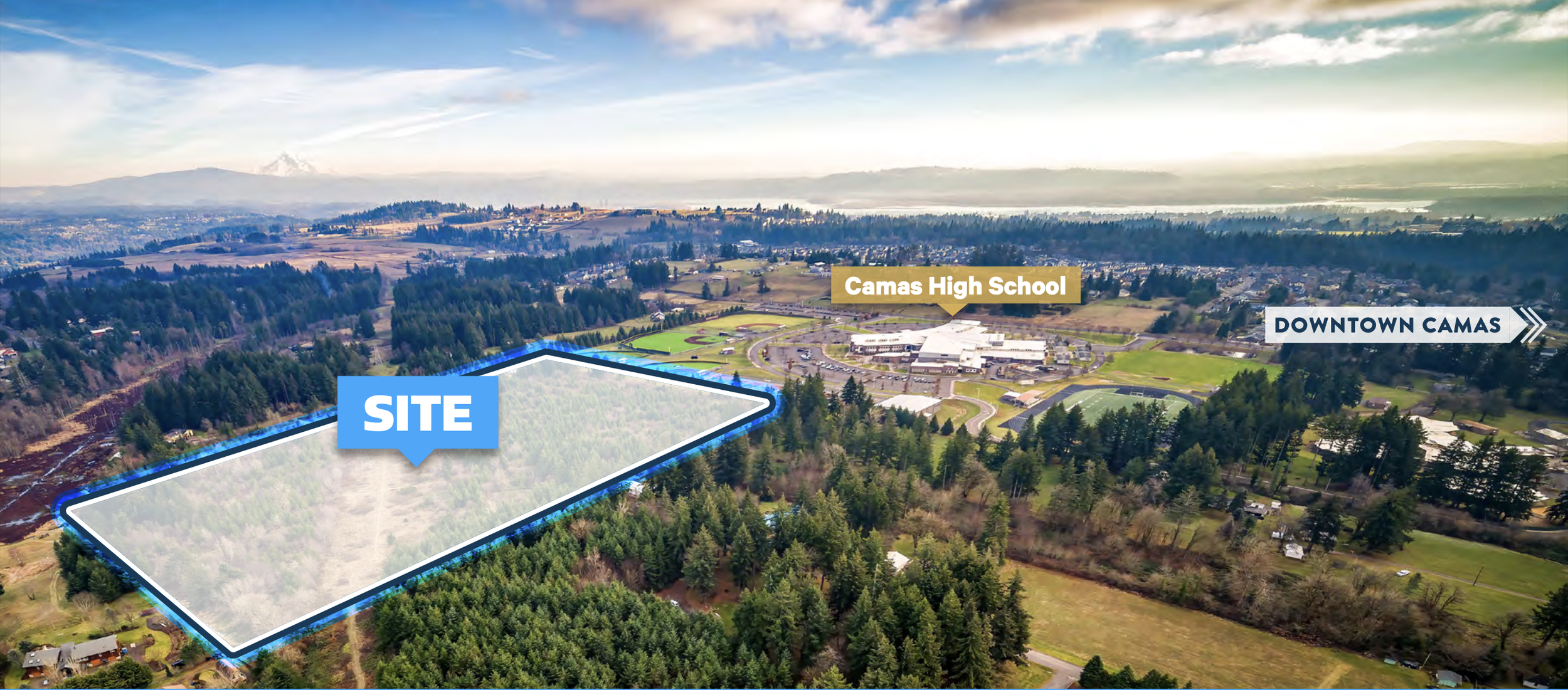 Aerial view of a large rectangular forested site marked as 'SITE' with a blue border, adjacent to Camas High School and near downtown Camas, with a scenic landscape and mountains in the background.