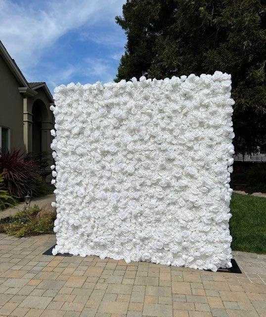White floral backdrop on a outdoor patio with a house and trees in the background.