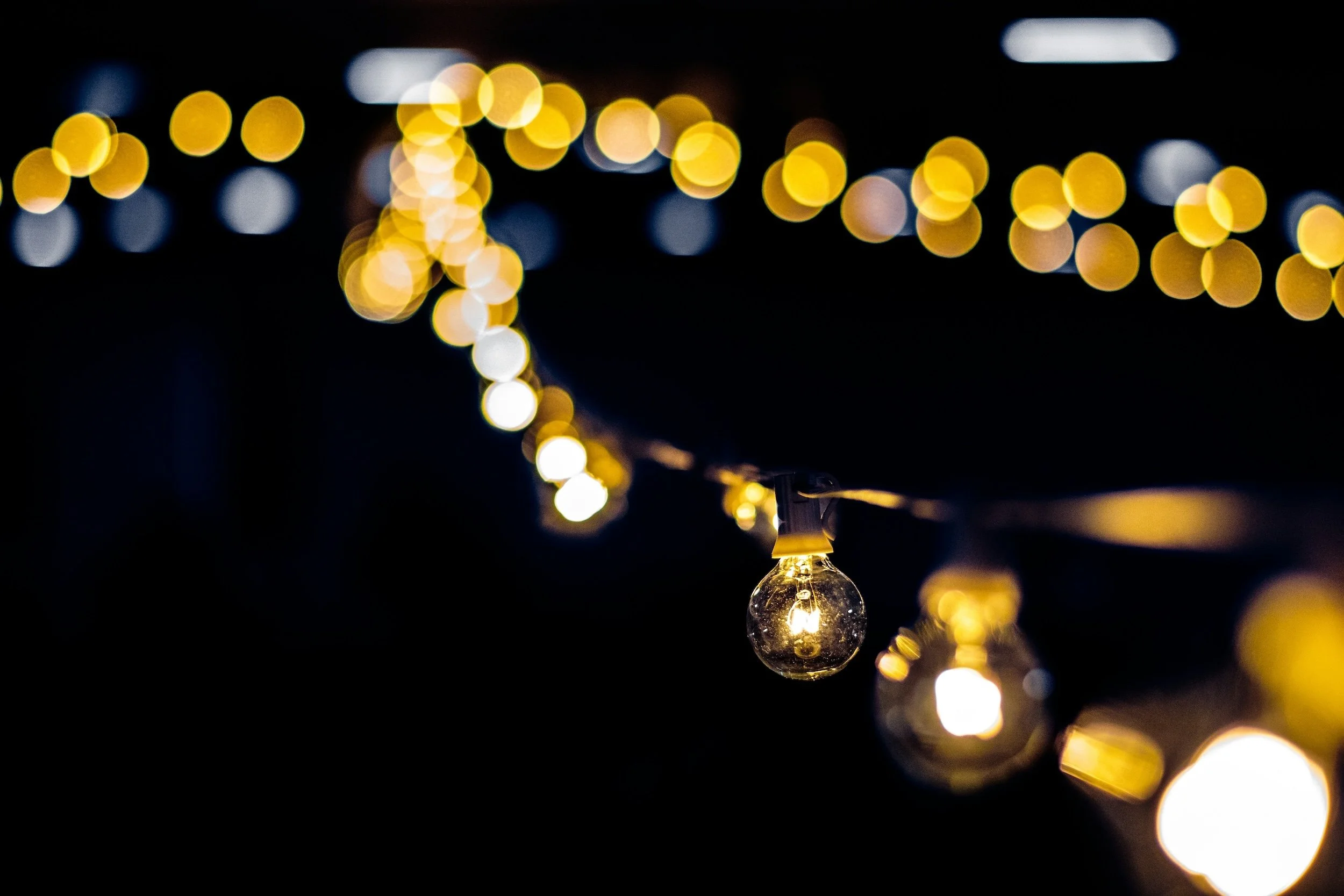 String of warm yellow string lights against a dark background, with some lights in sharp focus and others blurred.