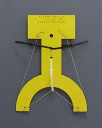 A yellow security tag with black pins, hanging on a gray surface.