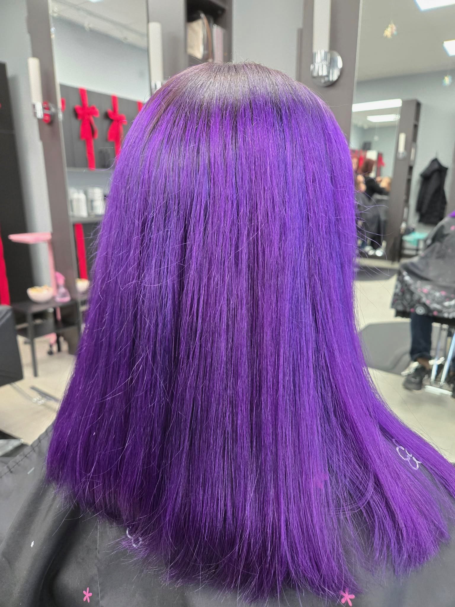 Back view of a person's head with straight, shoulder-length hair colored in vibrant purple.
