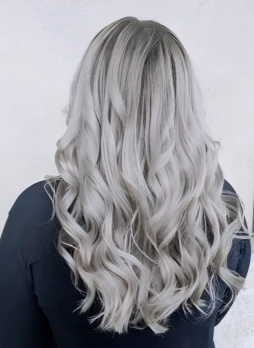 Back view of a woman with long, wavy, platinum blonde hair wearing a dark jacket