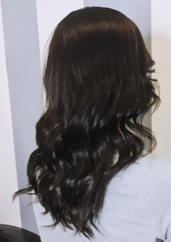 Side view of a woman with long, dark, wavy hair.
