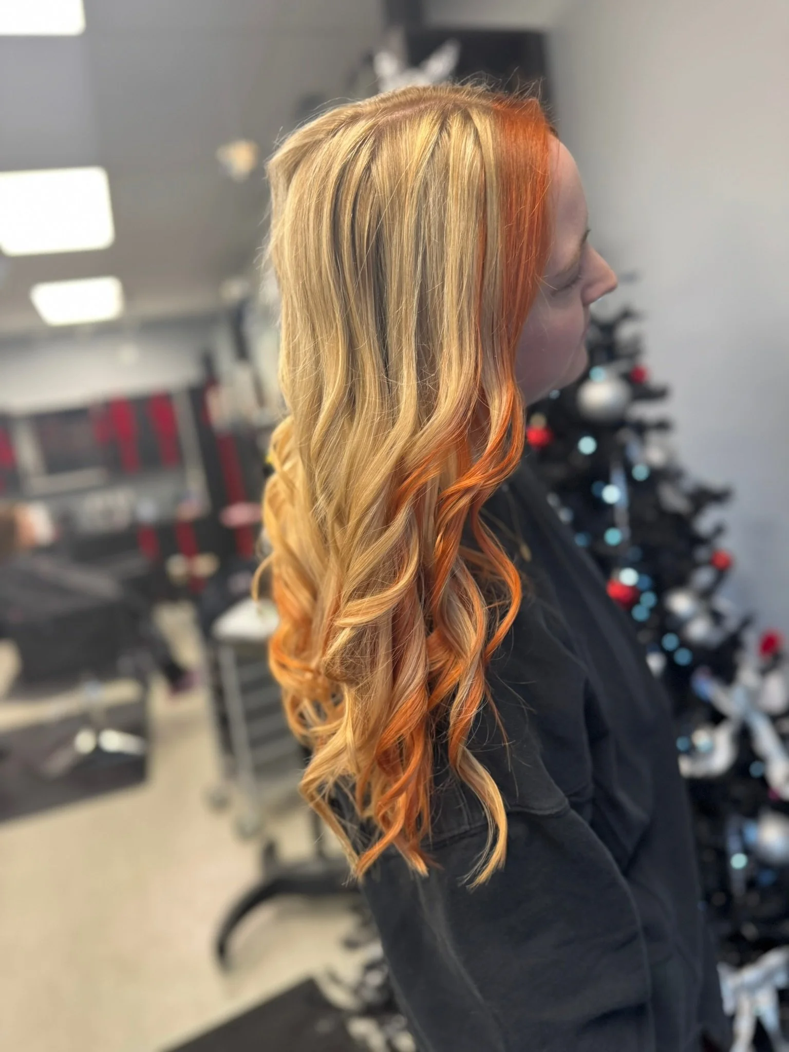 Woman with long, wavy blonde hair with orange highlights.