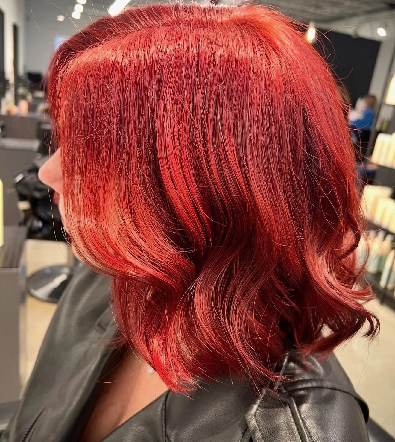 Woman with shoulder-length, wavy red hair in a salon chair.