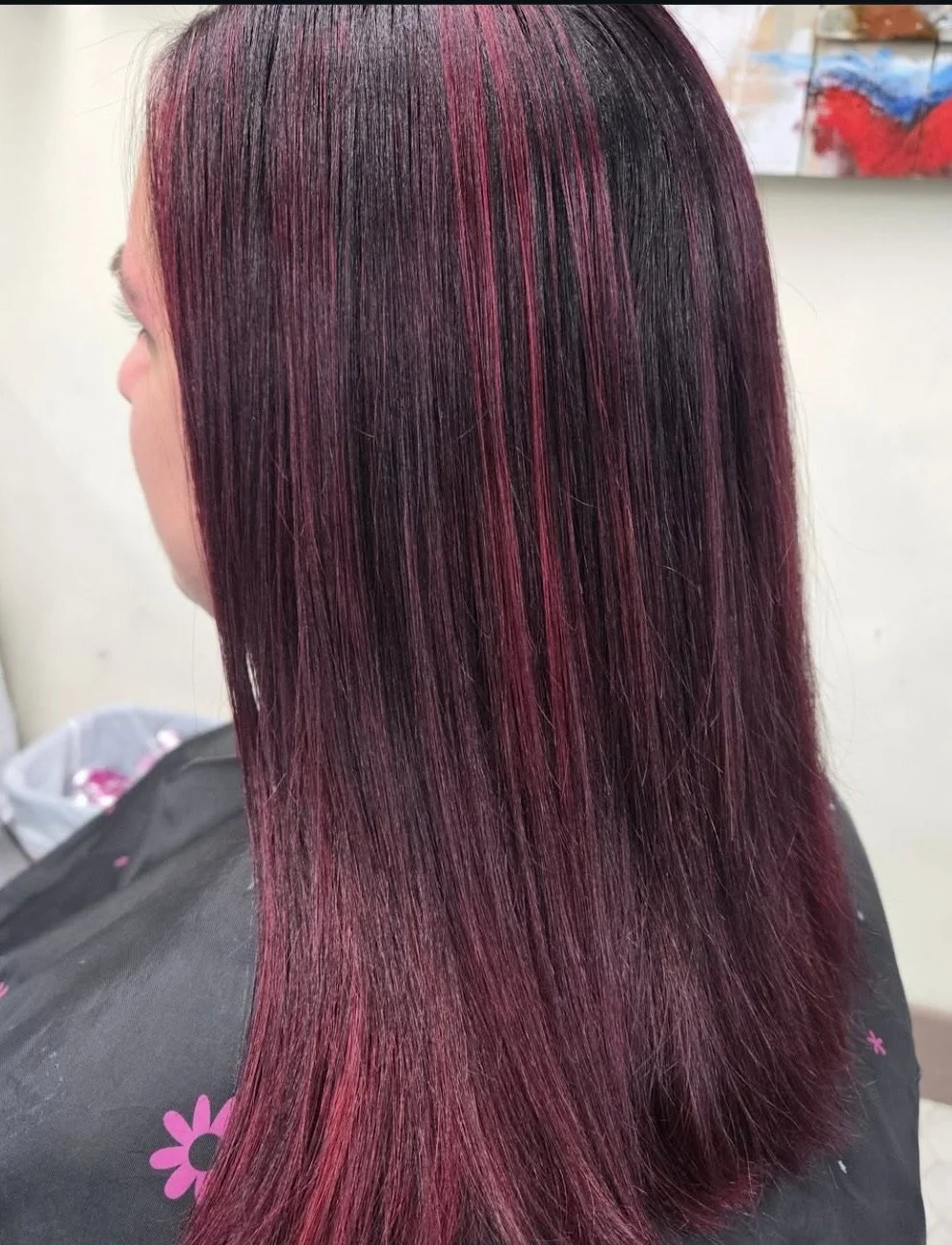 Side view of a woman with straight, dark hair with pink highlights.