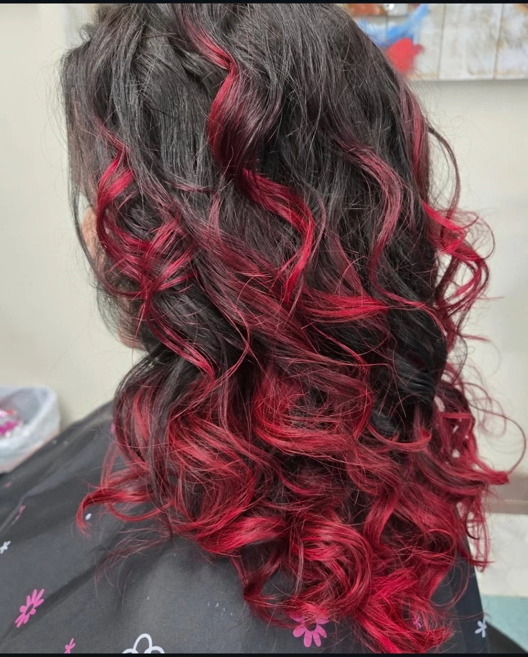 Back view of wavy black hair with red highlights and curls.