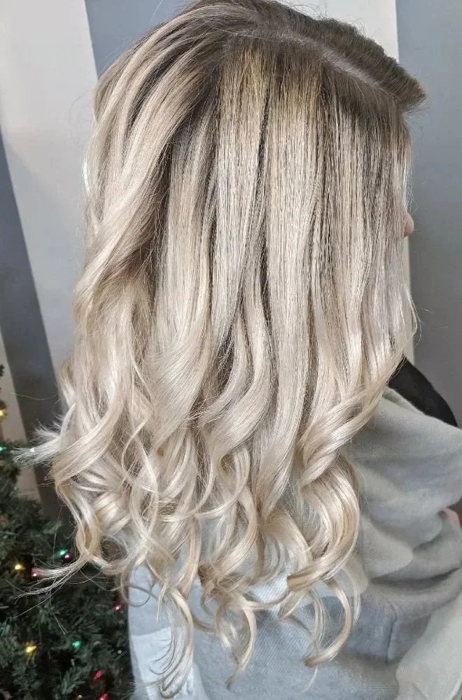 Side view of a woman with long, curly, platinum blonde hair.