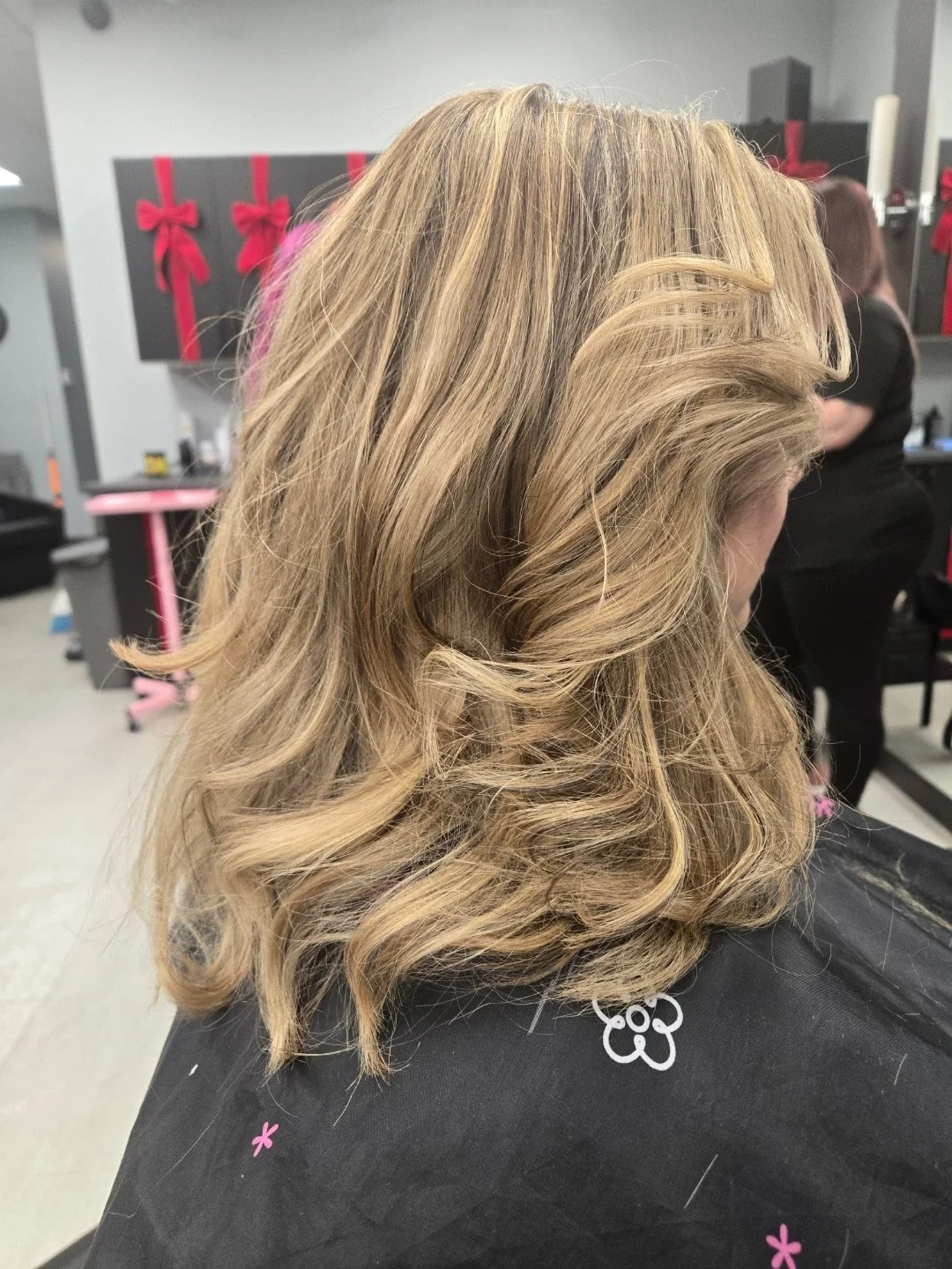 A woman with shoulder-length, wavy blonde hair in a hair salon.