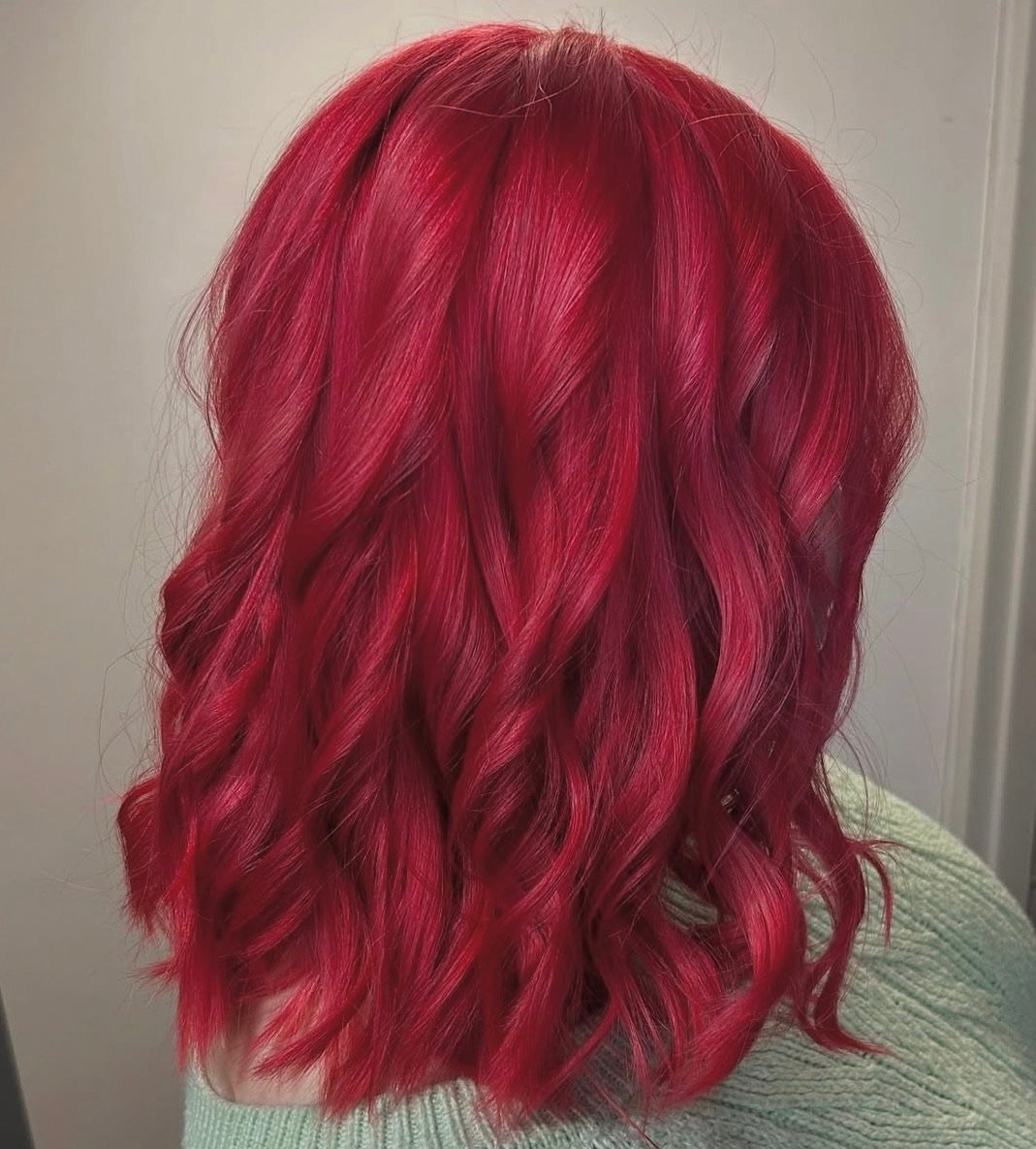 Back view of a person's head with vibrant red, wavy, shoulder-length hair.