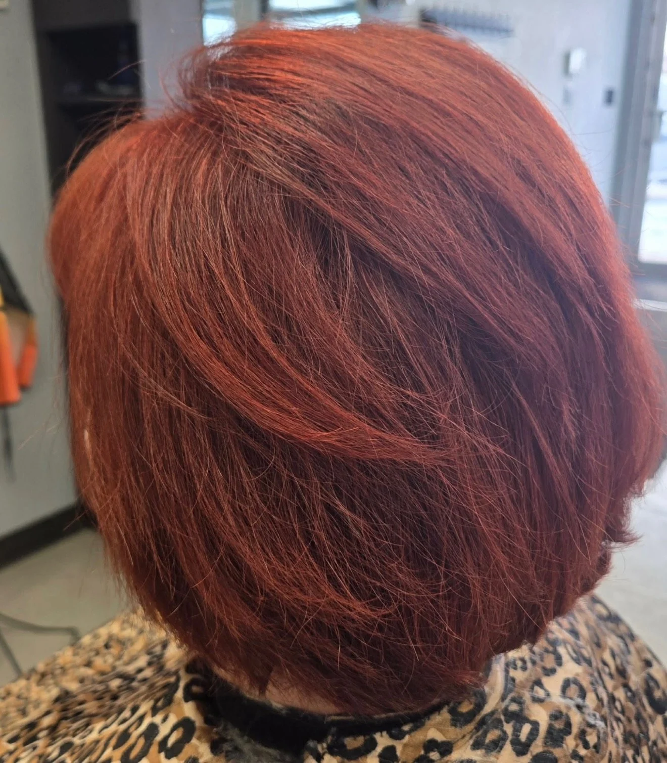 Close-up of a person's head with short, layered, reddish-orange hair.