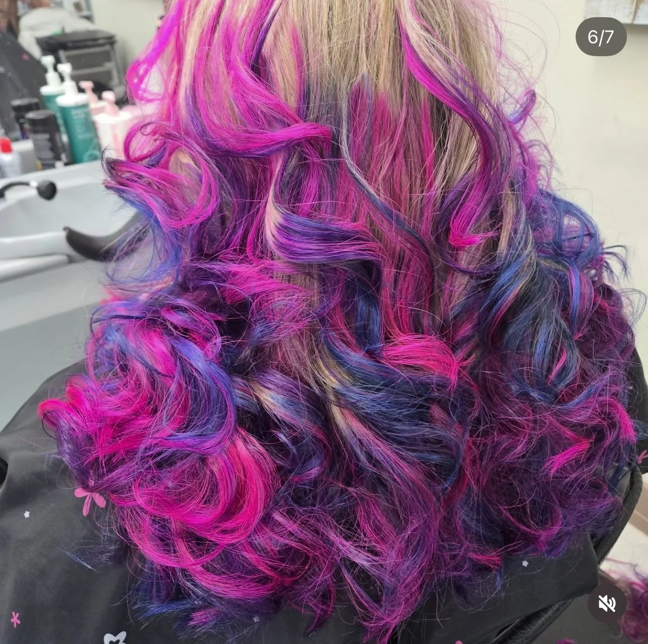 Colorful, curly hair with shades of pink, purple, and blonde, styled in tight curls.