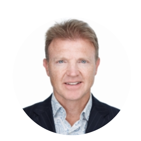 Portret van een man met lichtbruin haar, blauwe ogen, in een zwarte jas en een lichte blouse, tegen een witte achtergrond.