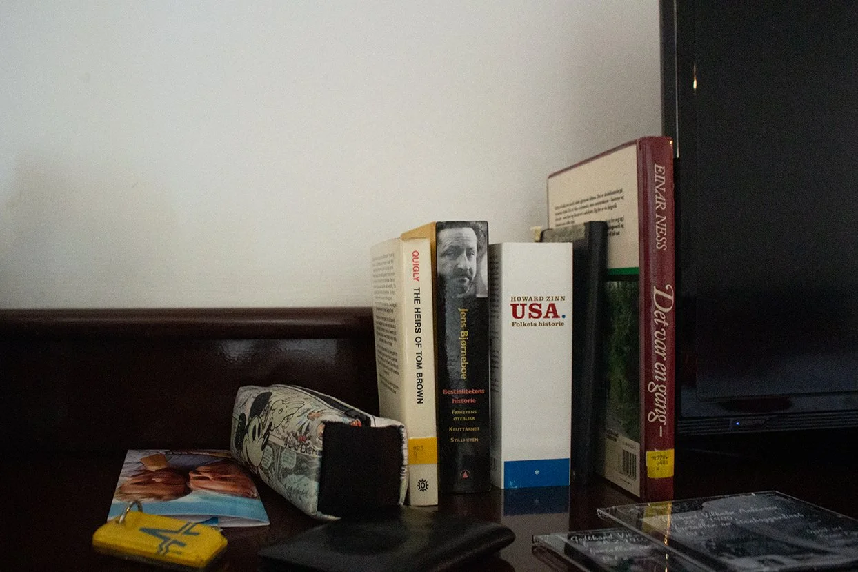 Books on a dark surface beside a TV, with a Mickey Mouse stress ball and some photographs.