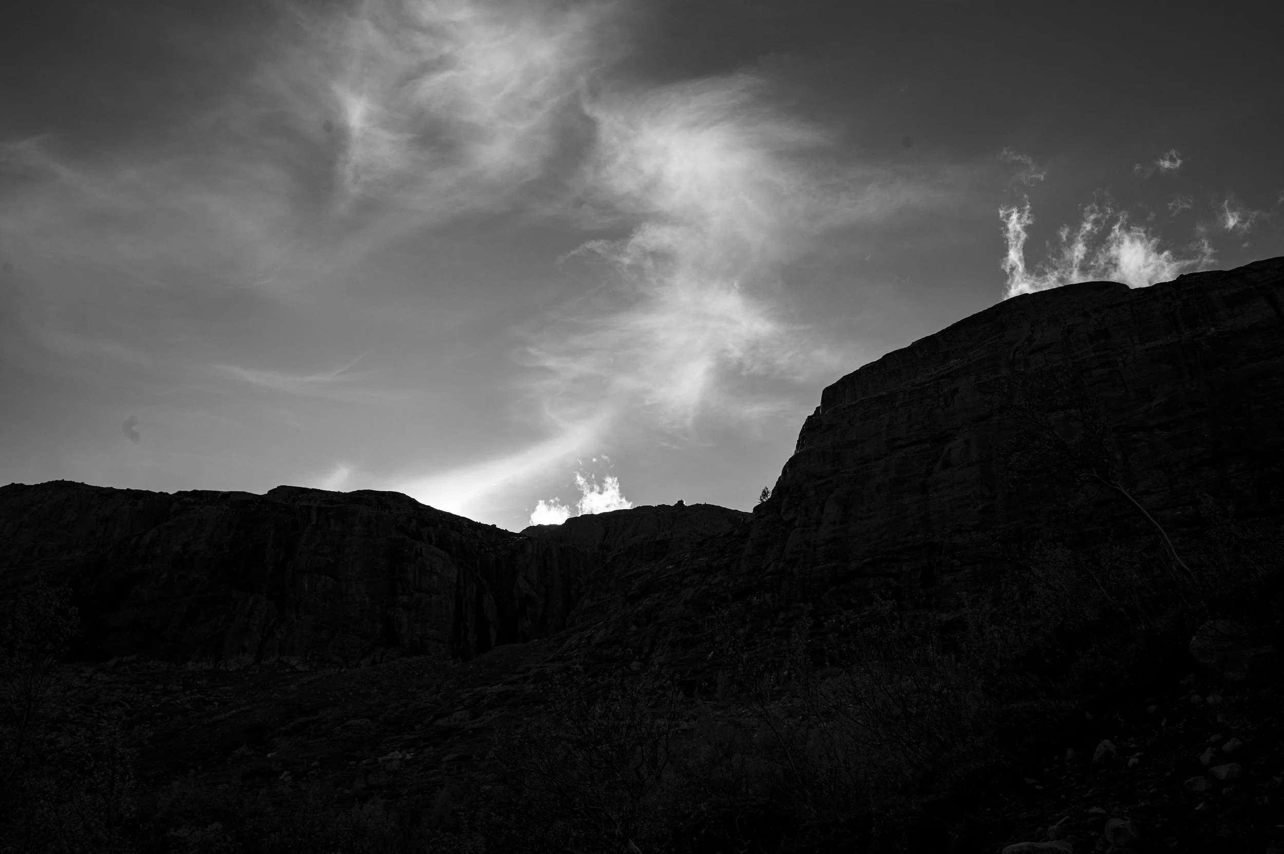 Silhouetted mountain range with cloudy sky in black and white.